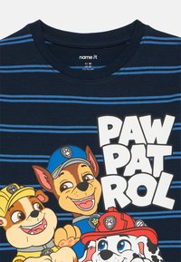 Granatowy t-shirt w poziome niebieskie paski, z postaciami kreskówkowymi psów z "Psi Patrol" oraz wyraźnym białym napisem "PAW PATROL".