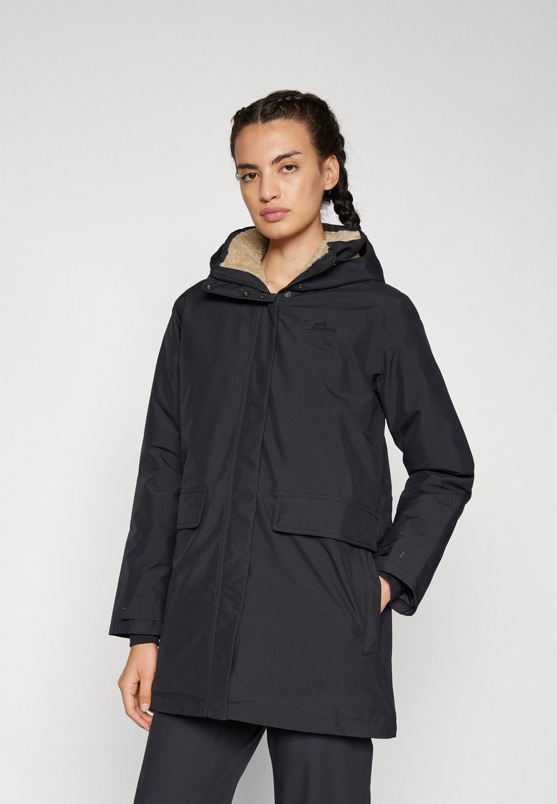 Parka noire imperméable avec capuche, dotée d'une douce doublure en fourrure brun clair, de poches avant et d'une fermeture éclair. Marquage minimaliste visible.