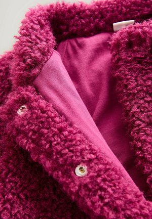 Flauschige, magentafarbene Außenschicht mit strukturiertem Stoff und einem glatten Innenfutter in einem ähnlichen Farbton. Verfügt über silberne Druckknöpfe.