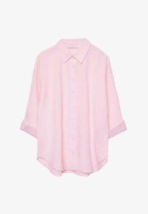 Jasnoróżowa koszula na guziki z długimi rękawami podwiniętymi do długości trzy czwarte oraz klasycznym kołnierzykiem.