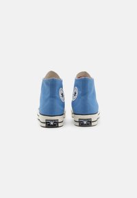 Sneakers alte blu in tela con cuciture bianche a contrasto, toppe rotonde con logo e suola in gomma con accenti neri.