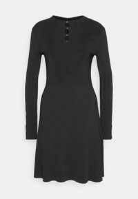 Robe noire en maille côtelée avec des manches longues, un col rond et trois boutons décoratifs dans le dos. Dotée d'une jupe évasée et d'ouvertures sur les côtés.