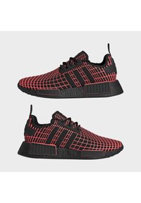 Černé sportovní boty s červeným mřížkovaným vzorem, s černými tkaničkami, texturovanou podrážkou a výrazným brandingem Adidas na boku a patě.