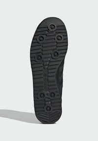 Black rubber shoe sole with multi-directional tread patterns, circular grips, and highlighted bars for traction and durability.