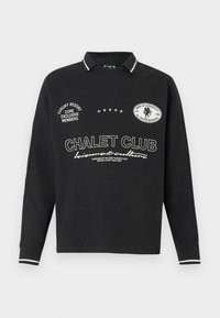 Sort langærmet polo med krave, med hvide tekster og logoer, stribede detaljer på kraven og ærmekanter. Afslappet, afslappet pasform.