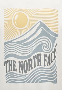 Ήλιος με ακτίνες πάνω από στυλιζαρισμένο βουνό και κυματιστά κύματα, με το κείμενο «THE NORTH FACE» παρακάτω σε έντονα γράμματα.