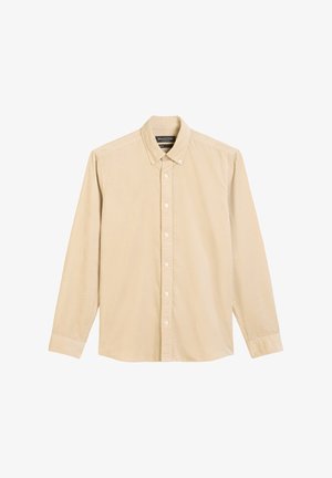 Chemise boutonnée en velours côtelé beige à manches longues avec un col à boutons et une étiquette sur la poche avant.