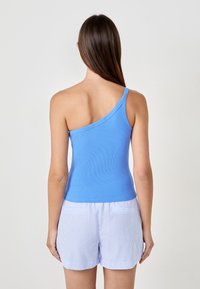Top azzurro chiaro, a coste, con design monospalla e aderente. Abbinato a pantaloni corti a righe bianche e blu. Texture liscia, stile minimalista.