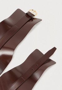 Barna bőr öv fényes felülettel, arany fém csattal. Texturált heveder több állítólyukkal és elkeskenyedő végekkel.