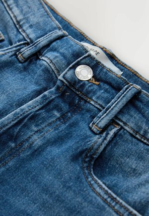 Light blue denim jeans with a zip fly and metal button closure. Features contrasting stitching and a classic five-pocket design.