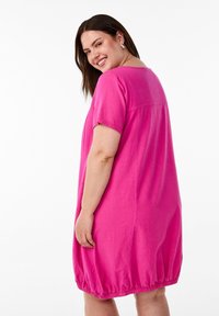 Fuchsiové bavlněné šaty s krátkými rukávy a elastickým lemem. Mají volný střih a jednoduchý design, ukazují hladkou texturu.
