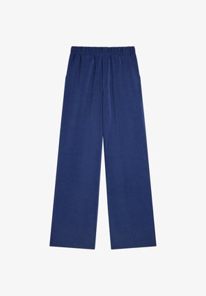 Szerokie granatowe spodnie z miękkiego materiału, elastycznym pasem, dwoma bocznymi kieszeniami i gładką fakturą. Brak widocznych wzorów lub metalowych elementów.