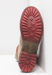 Brun suede støvle sål med en tekstureret rød gummiydersål, der har et mønstret greb og logo, størrelse 37, med et rundt tådesign.