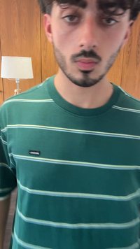 T-shirt verde riscado com listras horizontais em verde claro e branco, feito de um tecido suave. Pequeno logo preto na área do peito esquerdo.
