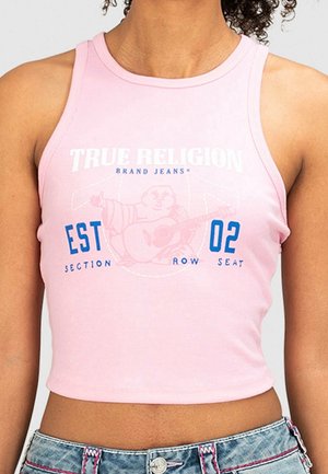 Kobieta nosząca różowy krótki top z białym i niebieskim logo True Religion na dżinsach oraz jeansy z różowym przeszyciem.