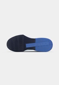 Semelle de chaussure de sport noire avec un motif de grip texturé, accent bleu et détail de logo surélevé. Le design offre traction et stabilité.