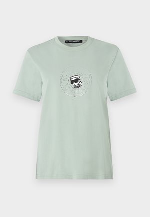 Hellminzgrünes Baumwoll-T-Shirt mit einem runden Grafikaufdruck, der eine Figur mit Sonnenbrille zeigt, umgeben von kleinen funkelnden Details.