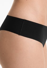 Zwarte naadloze ondergoed gemaakt van zachte stof, met een glad ontwerp en een elastische tailleband. Close-up weergave die de vorm en textuur benadrukt.