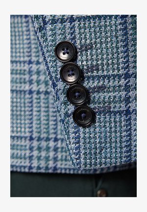 Kurtka w wielu kolorach w niebiesko-zielony wzór w jodełkę z czterema czarnymi guzikami na mankietach. Tekstura materiału jest tkana i strukturalna.