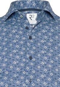 Blauw gebloemd shirt met een bloemenpatroon, met witte bloemen en gebogen bladeren. Het heeft een knoopsluiting aan de voorkant en een standaard kraag.