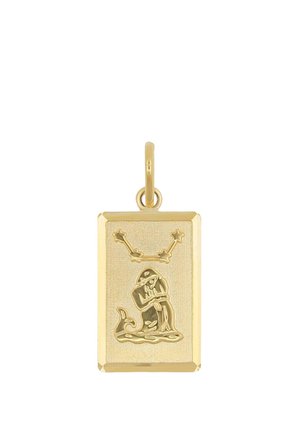 Donna che indossa un top beige senza maniche e una collana con pendente rettangolare in oro con un motivo inciso su una catena sottile.