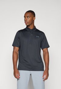 Crna polo majica od teksturirane tkanine s diskretnim uzorkom, kratkim rukavima i ovratnikom. Logo Under Armour u tamno sivoj boji na lijevoj strani prsnog dijela.