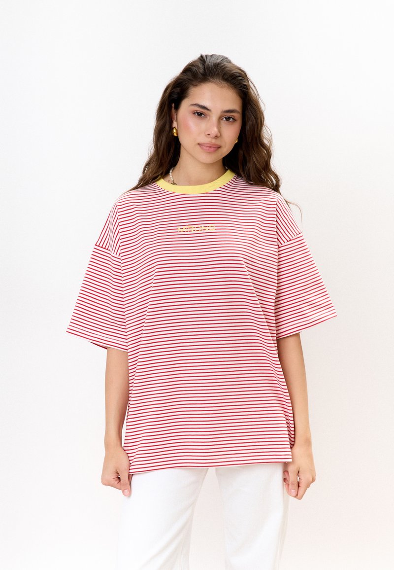 Rood-wit gestreepte oversized t-shirt met een gele kraag en een klein logo op de borst. Katoenen materiaal, korte mouwen, losse pasvorm.