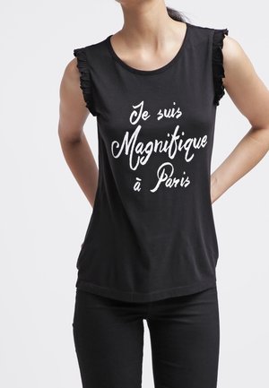 Sort ærmeløst top med flæsedetaljer på skuldrene, med hvid tekst, der lyder "Je suis Magnifique à Paris." Blødt stof, afslappet pasform.
