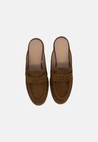 Mule in suede marrone con una fascia e dettagli in metallo dorato. Punta arrotondata, soletta imbottita e cuciture testurizzate lungo i bordi.