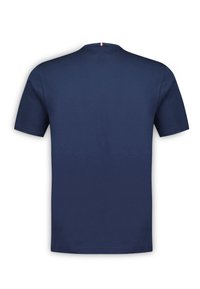 Navy blue cotton t-shirt with short sleeves. Features a crew neck and a small red and white accent at the back neck. Soft, smooth texture.