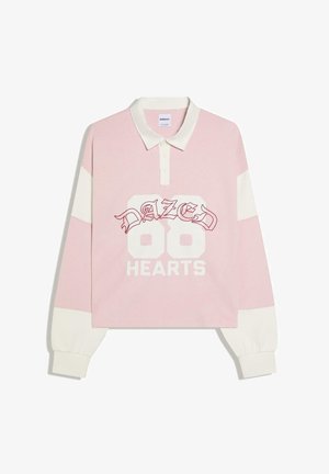 Langærmet pink og hvid rugbyshirt med hvid krave, knaplukning, teksten "DAZED 86 HEARTS" på forsiden og hvide ærmekanter.