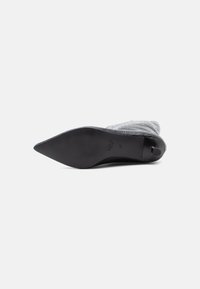 Scarpa con tacco alto a punta in materiale grigio con motivo coccodrillo, con suola nera elegante e tacco arrotondato. Taglia 37 visibile sulla parte inferiore.