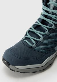 Donkerblauwe hikingboot met textuurstof en synthetische overlays, versterkte neuskap en lichtblauwe veters. Duurzame rubberen zool.