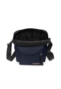 Laavansin sininen ristivartalolaukku, jossa on vetoketjulla suljettava yläosa, musta sisävuori, säädettävä hihna ja etutasku. Eastpak-logo esillä.