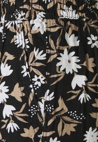 Czarna tkanina z kwiatowym wzorem z białymi i beżowymi kwiatami. Teksturowana powierzchnia z elastycznym paskiem w talii i plisowanymi detalami.
