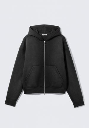 Sudadera con capucha negra con cremallera, hecha de tela suave, con un bolsillo frontal, capucha y puños acanalados. Diseño minimalista sin patrones visibles.
