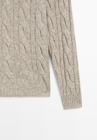 Pull en tricot torsadé beige clair avec des manches longues, design texturé, poignets et ourlet côtelés. Tissu doux et chaud avec un motif classique.