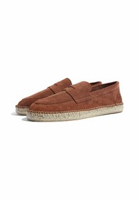 Smeđe ante cipele s okruglim prstom i dekorativnim šavovima. Detalj od jute užeta duž đona dodaje teksturu. Dizajn s zatvorenim stražnjim dijelom.