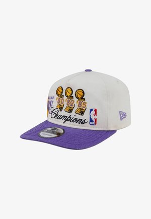 Witte en paarse basketbalpet met geborduurde NBA-trofeeën en jaren 1980, 1982, 1985, het woord "Champions" en het NBA-logo.