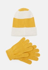 Gorro de malha amarelo e branco às riscas com um punho dobrável acima de luvas amarelas combinando, todas com uma textura canelada.