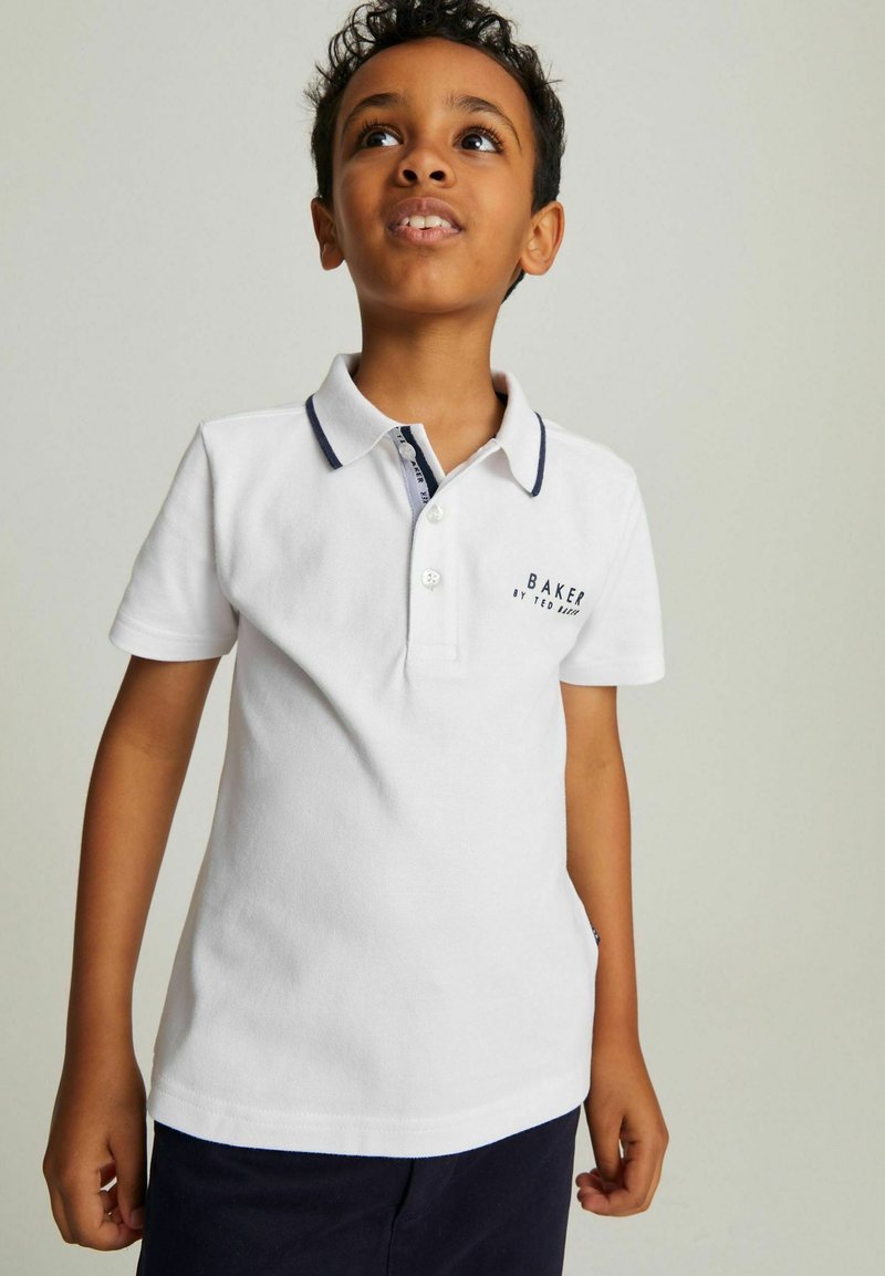 Biely polo tričko s krátkym rukávom a námorníckym golierom a zapínaním na gombíky. Na hrudi sa nachádza logo "BAKER by Ted Baker" v tmavom texte.