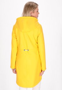 Rumena nepremočljiva jakna s kapuco, nastavljivim pasom, dolgimi rokavi in gladko teksturo. Zadnji pogled prikazuje zaobljen rob.