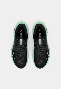 Baskets de course noires avec un dessus respirant, semelle vert menthe, détails réfléchissants et design de lacet texturé. Adaptées à un usage athlétique.