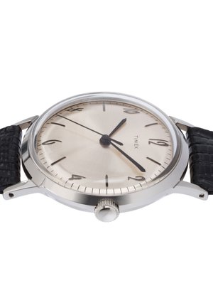 Srebrnokovinski okrogli ura s telesom iz nerjavečega jekla, svetlo srebrnim številčnikom, črnimi kazalci in teksturiranim črnim usnjenim trakom. Ima tudi krono.