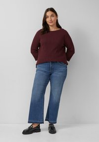 Bordeauxfarbener, strukturierten Pullover mit Rundhalsausschnitt, kombiniert mit blauen weiten Jeans und schwarzen Plateauslatschenschuhen, um ein lässiges Outfit zu kreieren.