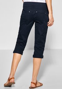 Námořnické zkrácené kalhoty s ohrnutými manžetami, plochým pasem a knoflíkovými zadními kapsami. Vyrobené z měkkého materiálu s hladkou texturou.