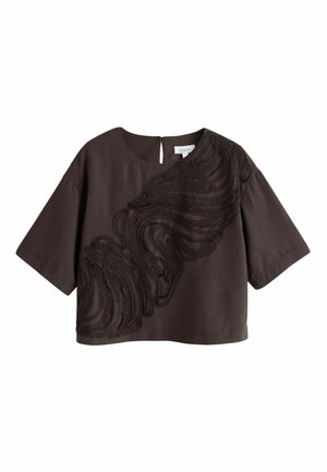 Tummanruskea lyhyt, lyhythihainen pusero, jossa on pyöreä pääntie ja abstrakti, teksturoitu kiertokuvio viistosti etuosassa.