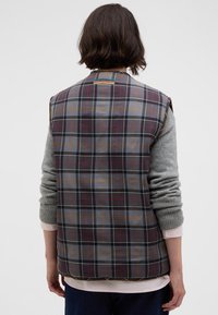 Kostkovaná vesta šedé a hnědé barvy, prošívaný design a šedé pletené rukávy. Obsahuje zaoblený límec a viditelné stehy.