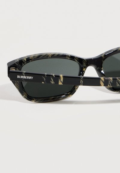 Ορθογώνια γυαλιά ηλίου με μαύρο και μπεζ μαρμάρινο σχέδιο, σκοτεινούς φακούς και το λογότυπο "BURBERRY" στο πλάι του βραχίονα, εμφανιζόμενα σε κοντινή λήψη.