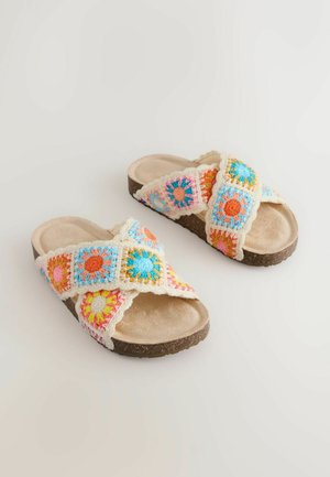 Bunte gehäkelte Slide-Sandalen mit gekreuzten Riemen und Blumenmustern in Pink, Blau und Orange auf einer strukturierten braunen Sohle.